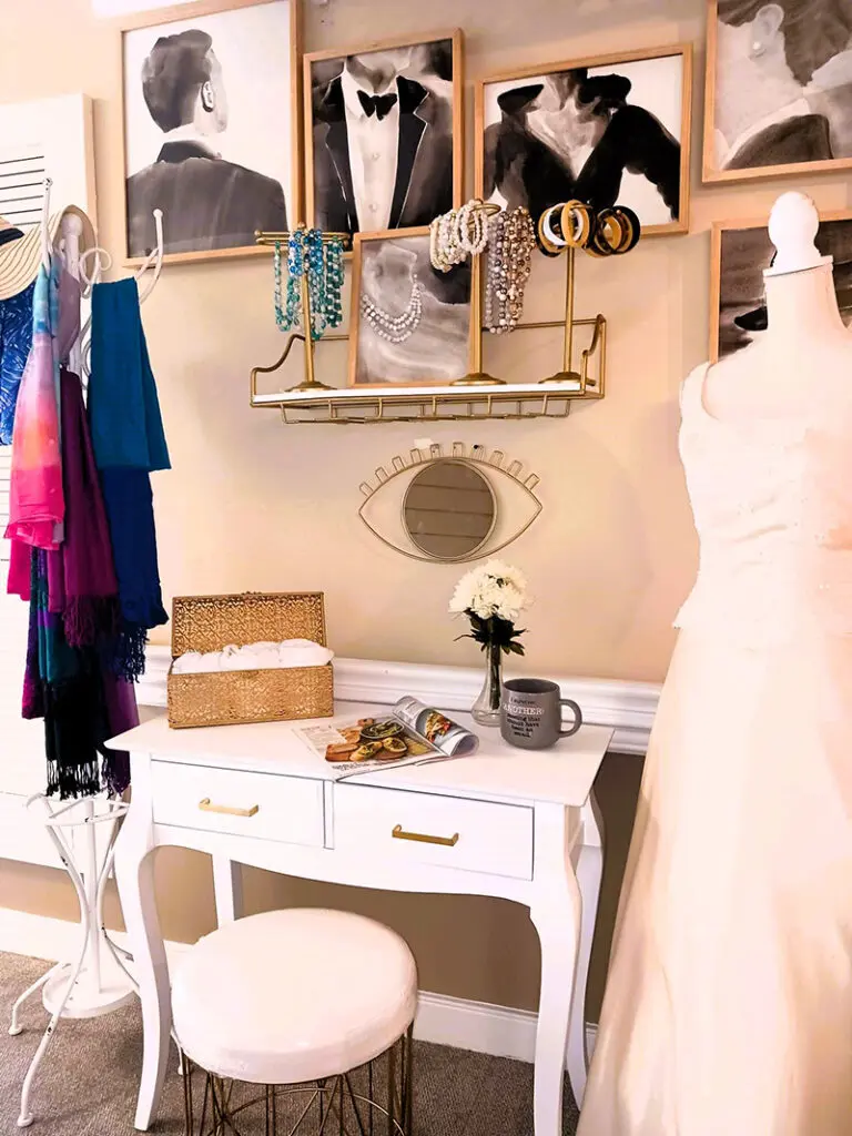 beautiful dress and scarves hanging next to vanity table under framed artwork